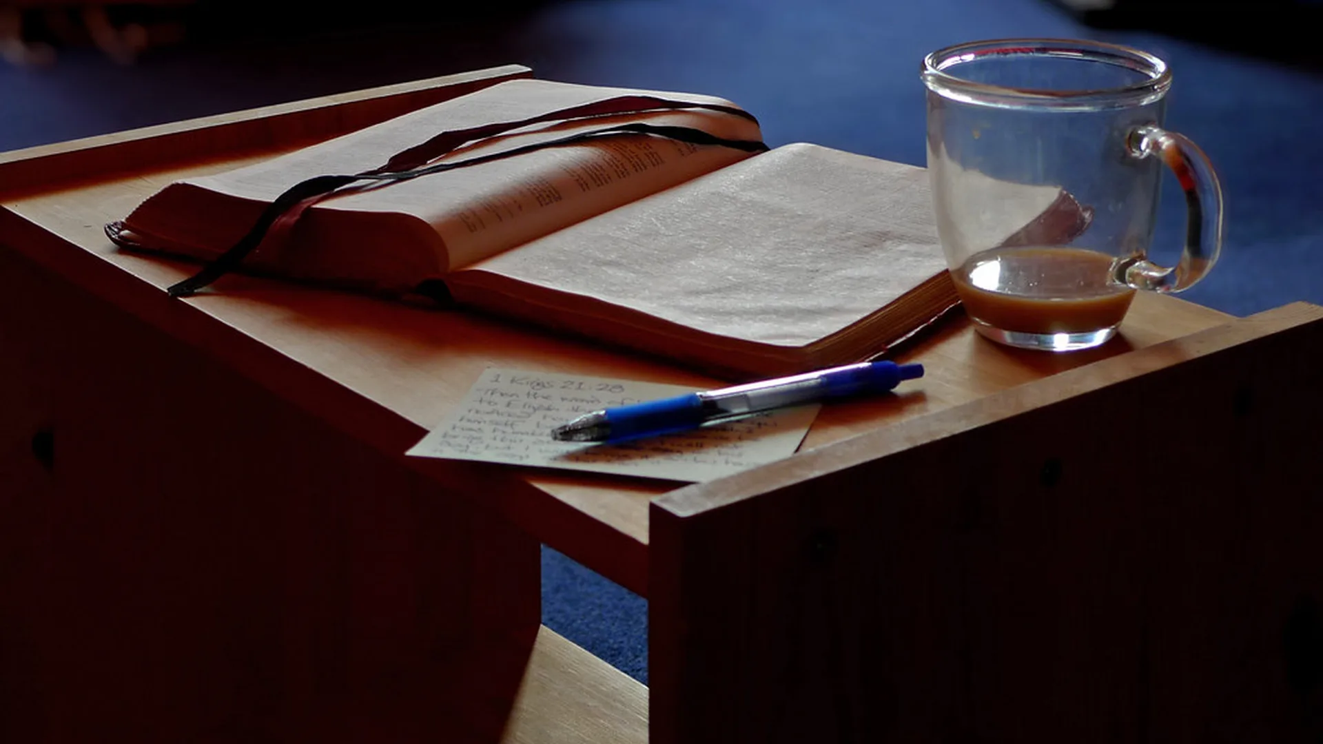 A handwritten journal open on a desk beside a cup of tea