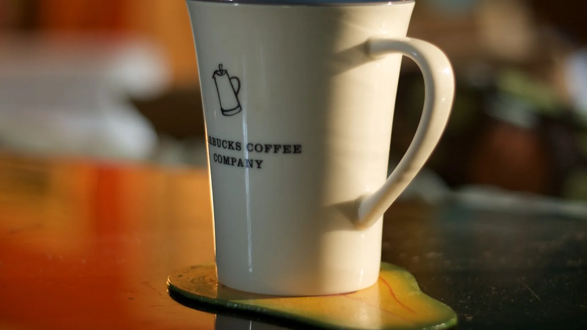 A person journaling with a warm cup of coffee at a wooden desk